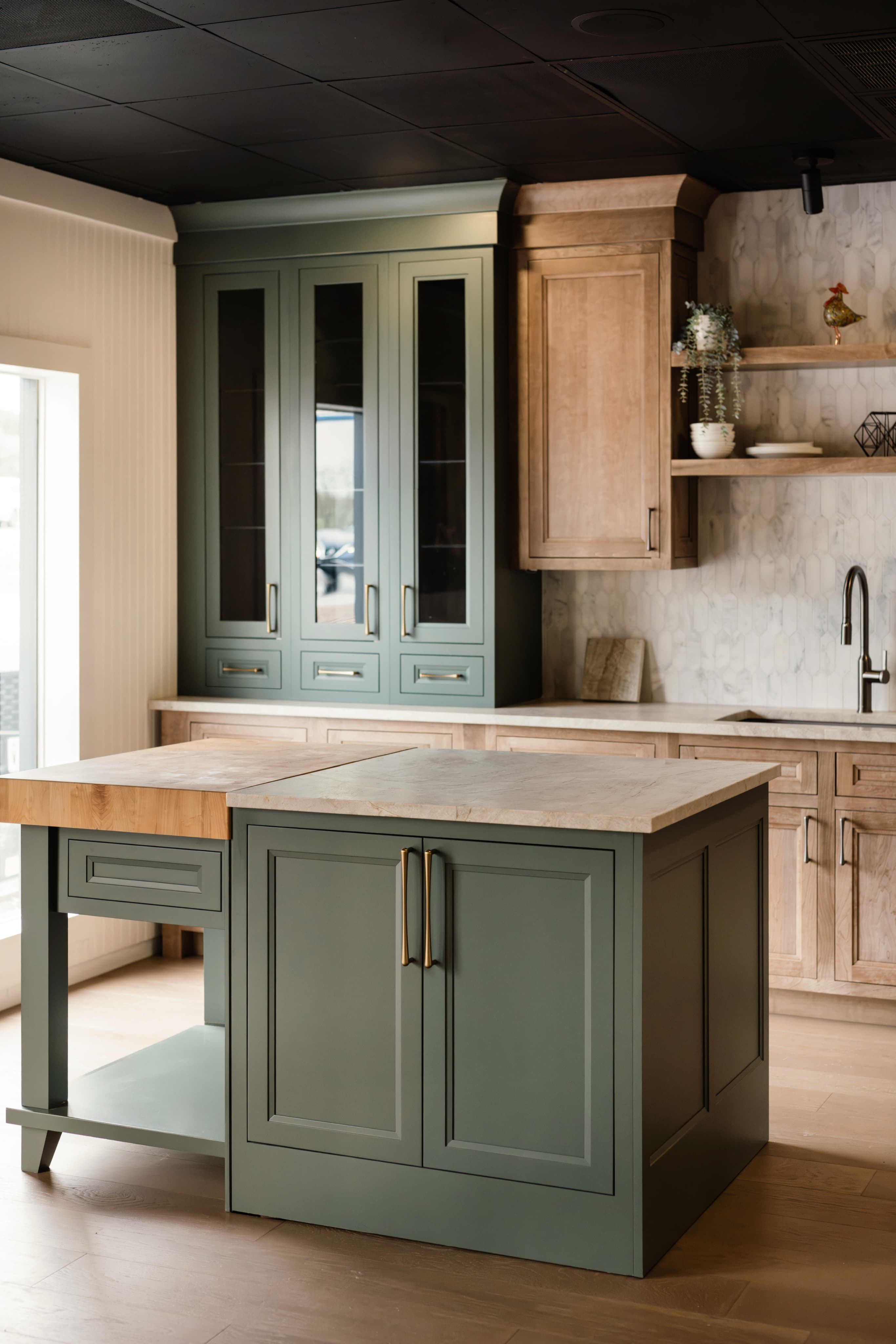 Cabinet materials — sage painted island next to natural wood pantry