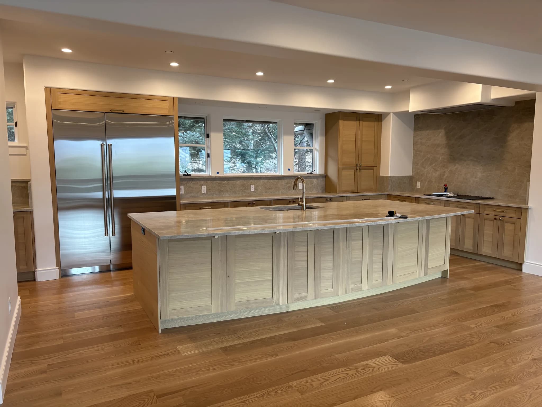 Light oak kitchen with a large island and built-in stainless refrigerator
