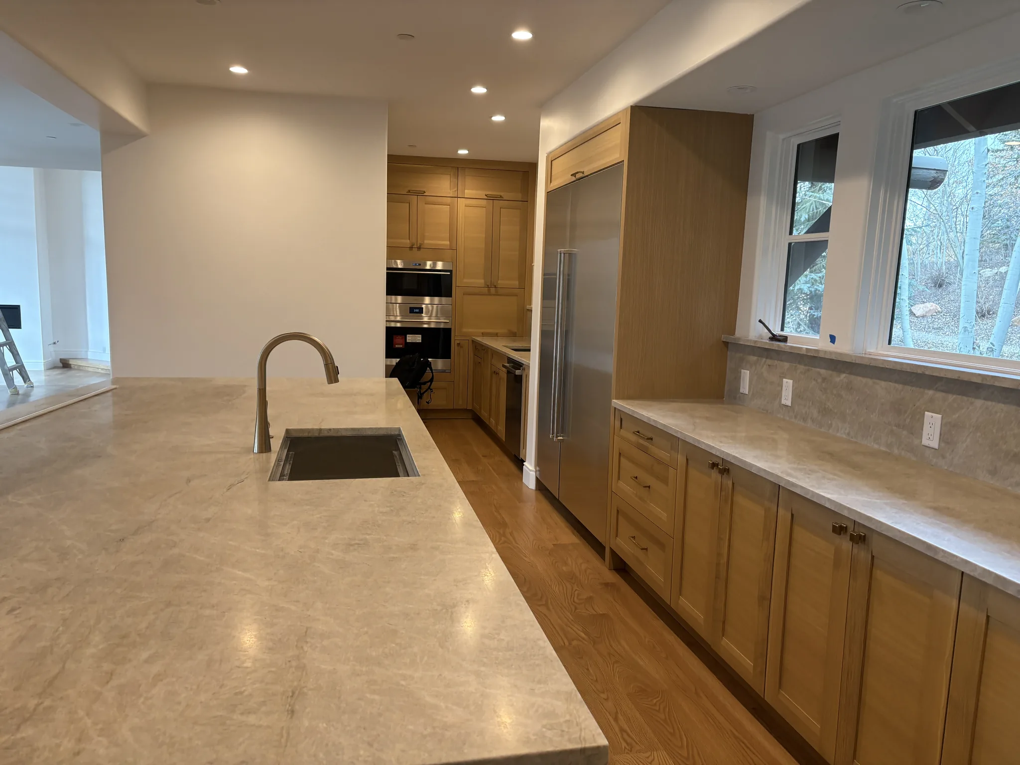 Light oak kitchen island with an integrated sink and stone countertops