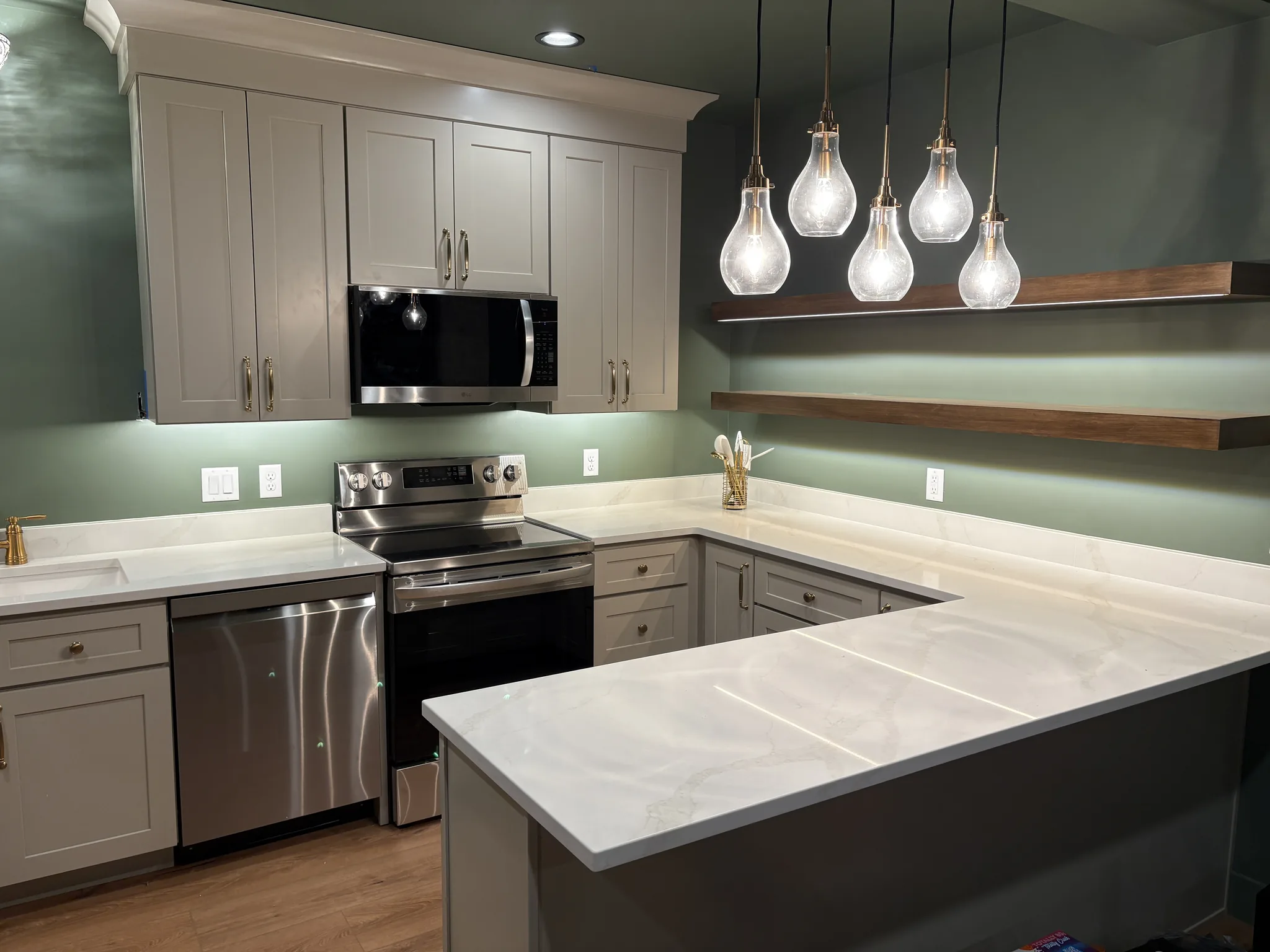 White shaker kitchen with a green accent wall and pendant lighting