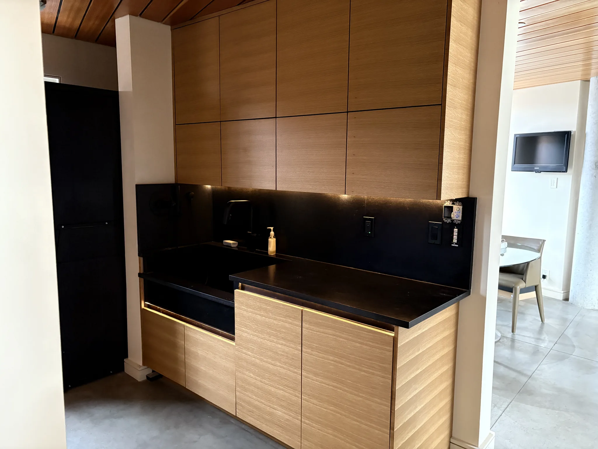 Butler's pantry with slatted wood cabinetry and a black stone counter