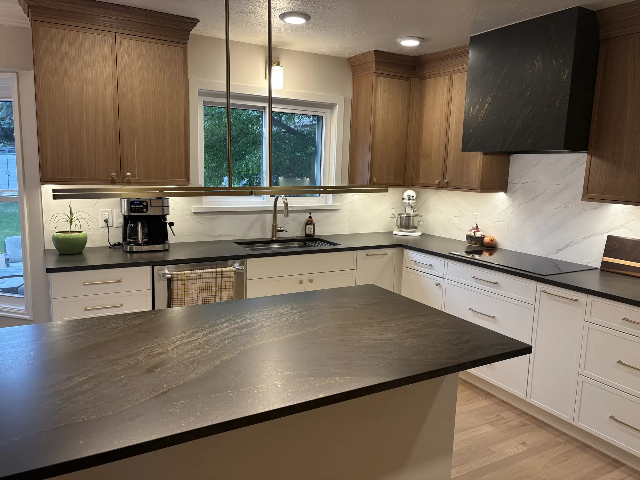 White and wood kitchen with dark stone countertops and a black range hood