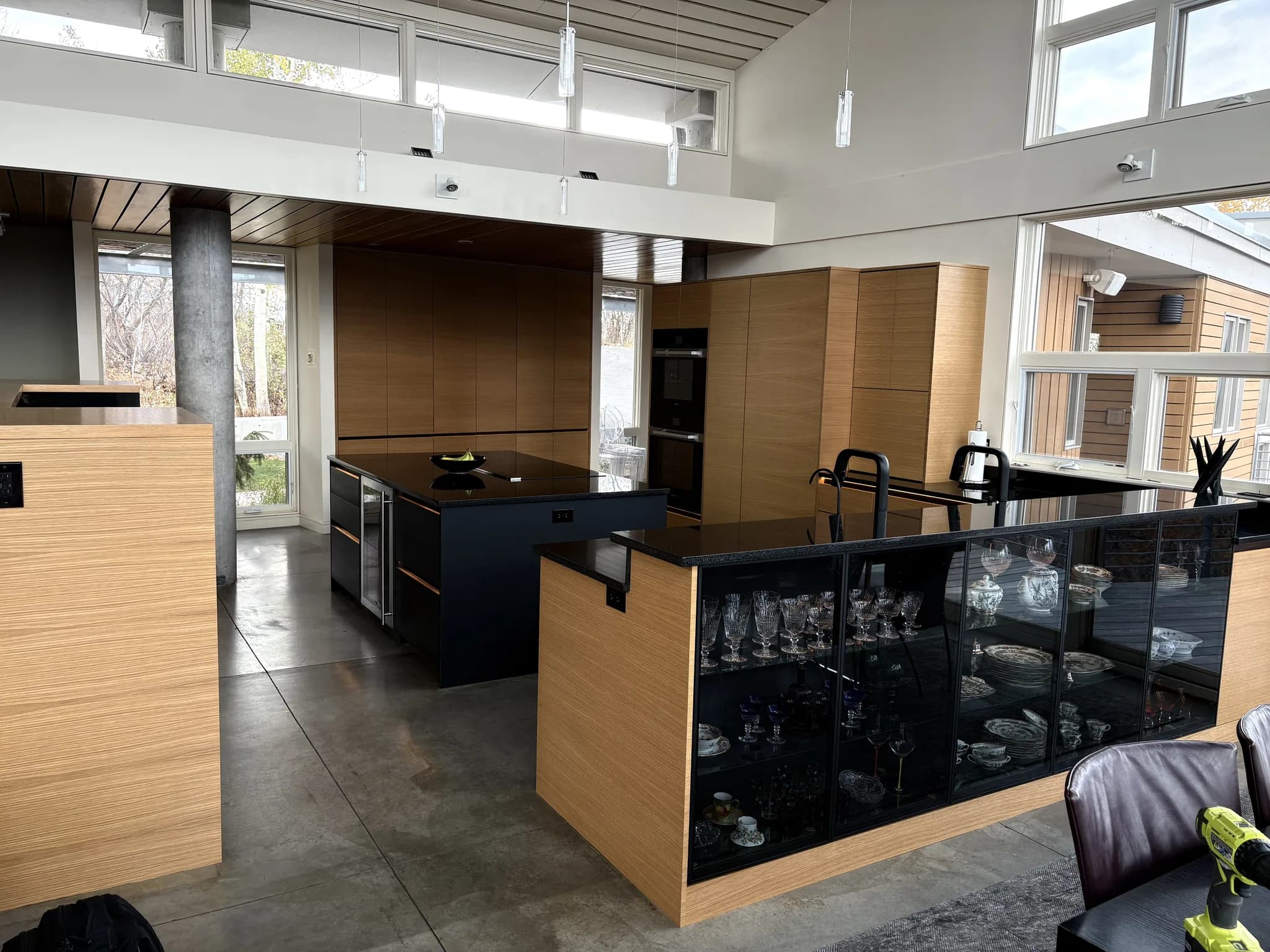 Open-plan modern kitchen with vertical-grain wood cabinetry and a black island