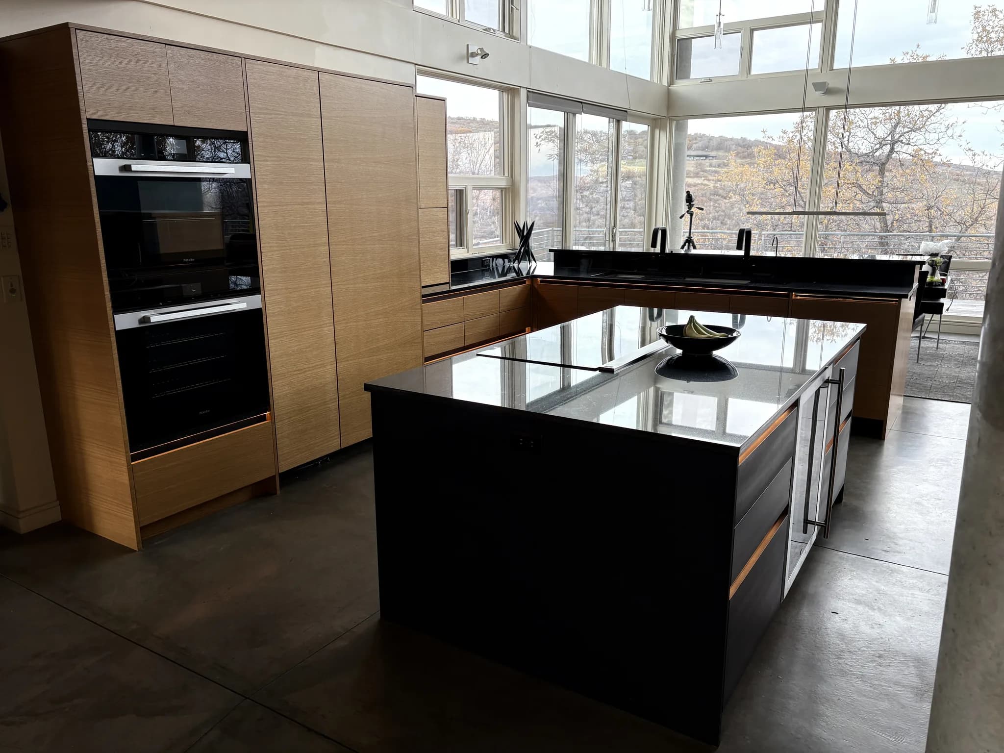 Modern kitchen with floor-to-ceiling wood cabinetry, wall ovens, and a black island