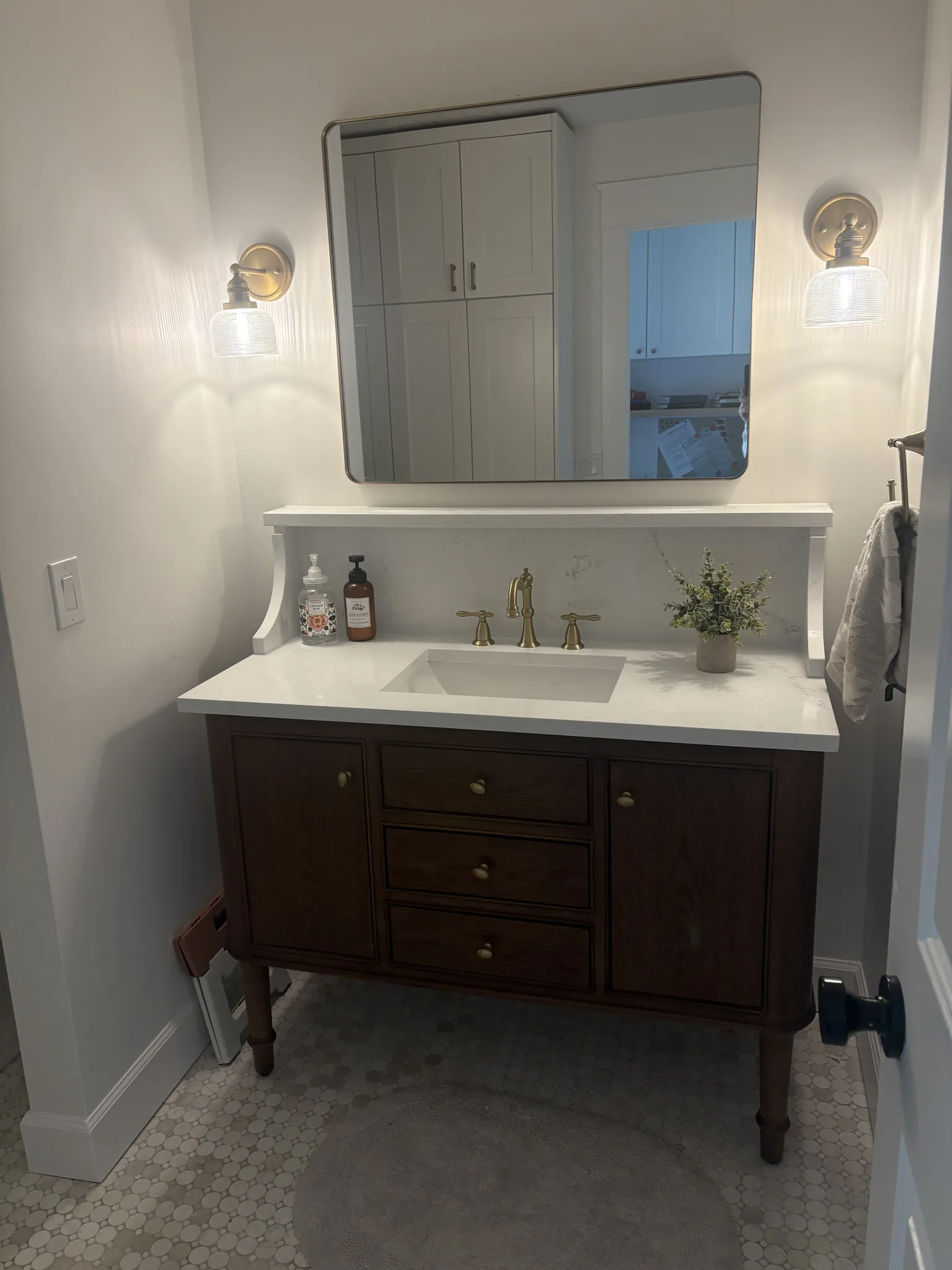 Powder bath with a dark wood vanity and white countertop