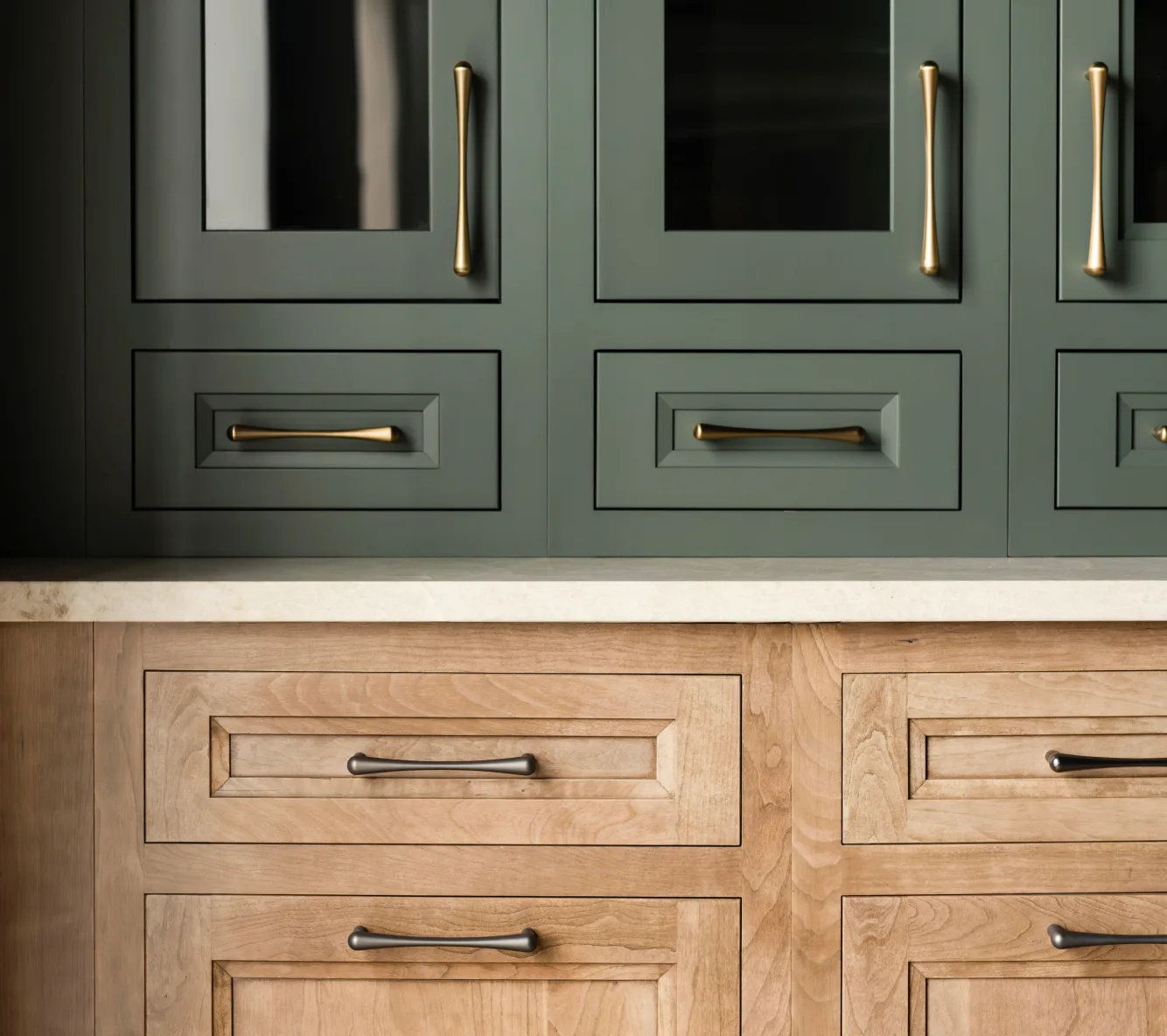 Detail of green glass-front cabinets above natural wood drawers