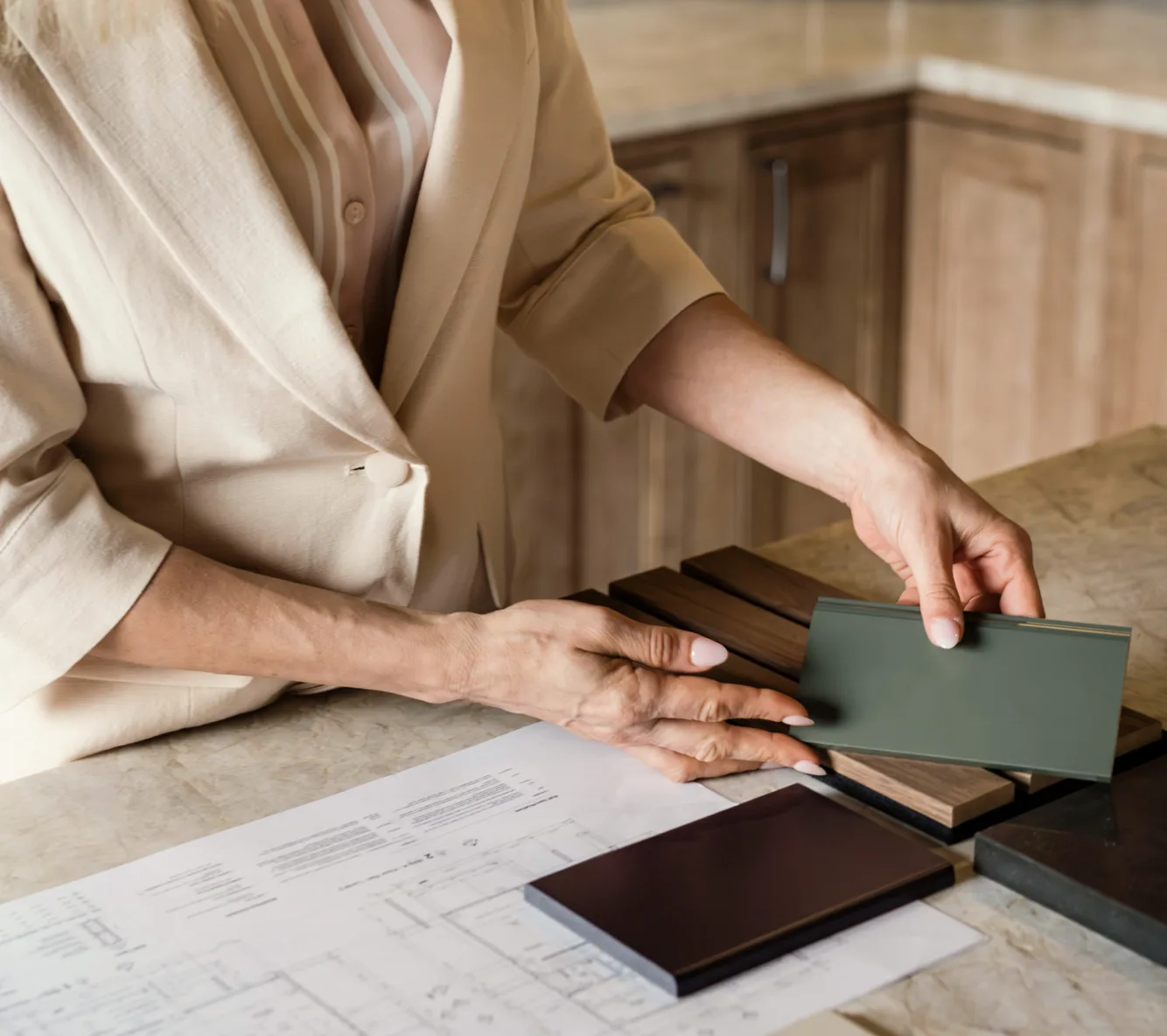Designer comparing cabinet finish samples over kitchen plans
