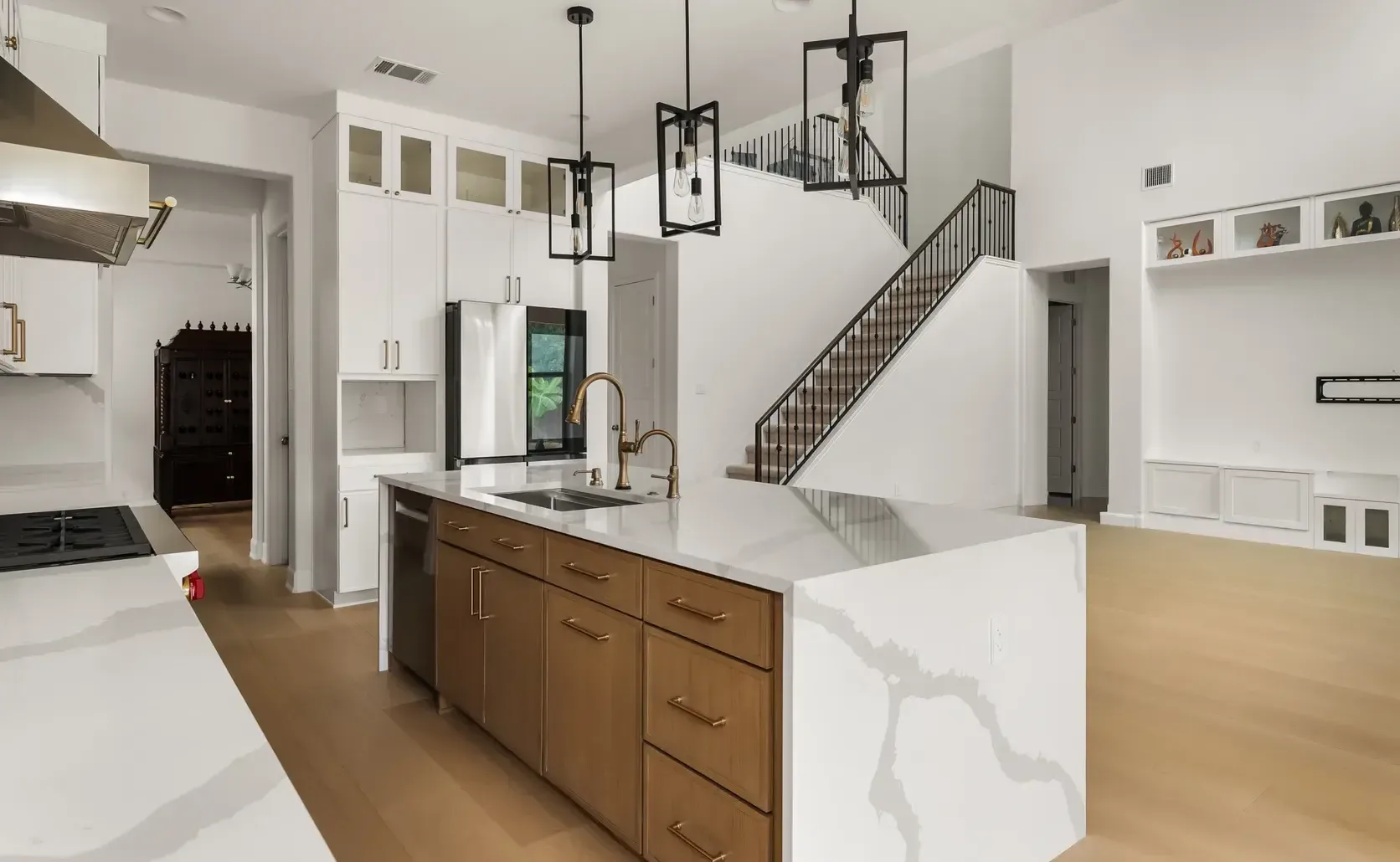 New construction kitchen with white upper cabinets, wood island and waterfall quartz countertop